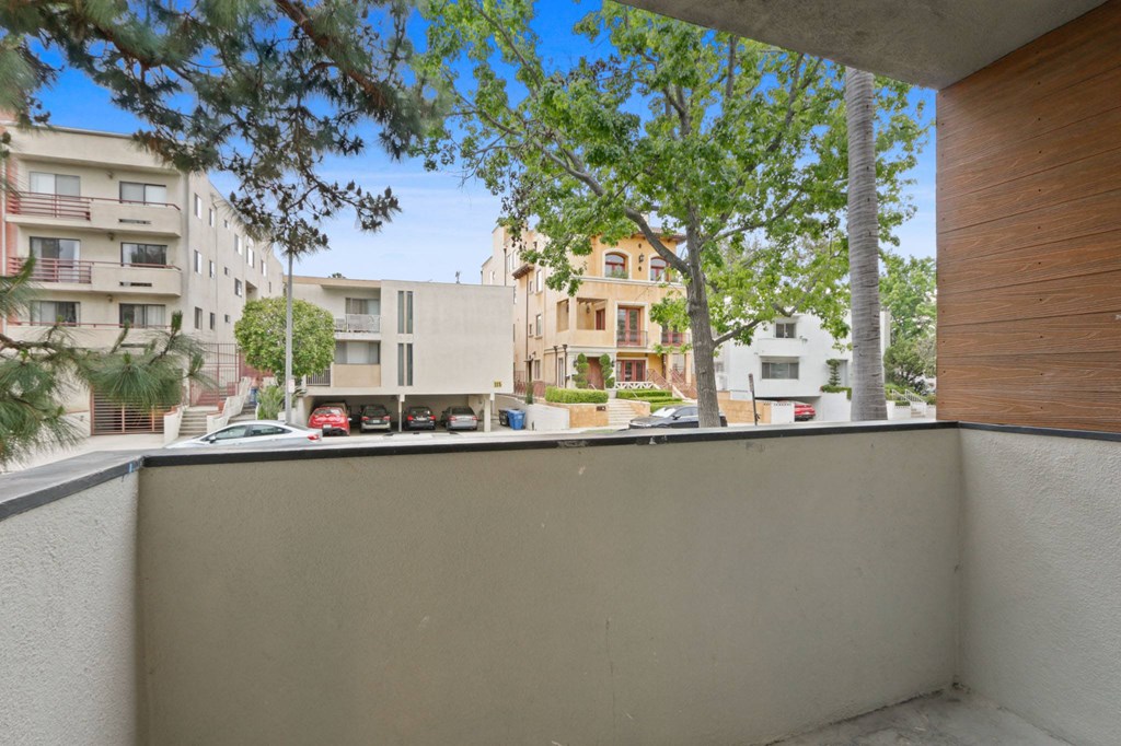 a balcony with a view of a city street and trees