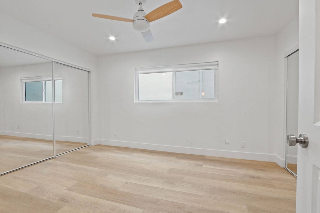 an empty room with a glass door and a ceiling fan