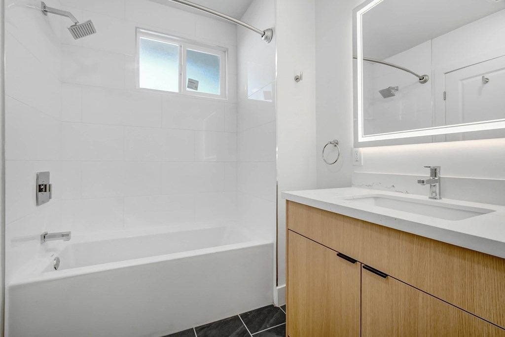 A white bathroom with a wooden cabinet and a white sink.