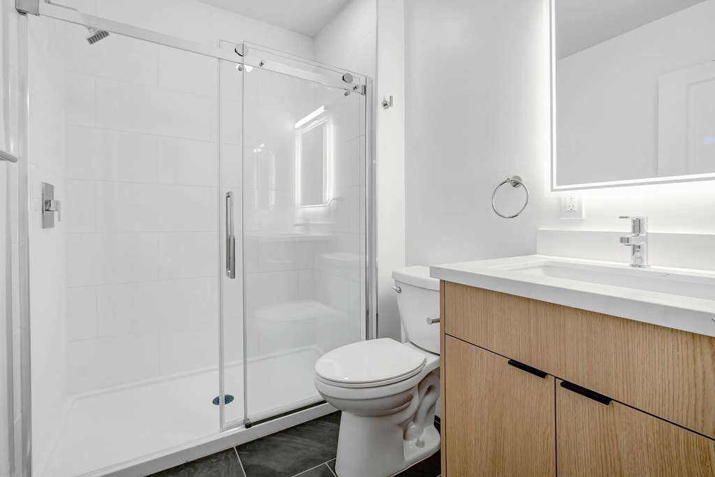 A white bathroom with a toilet, sink, and shower.