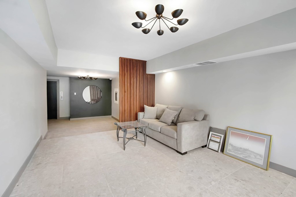 A living room with a couch, chair, and a picture frame on the floor.