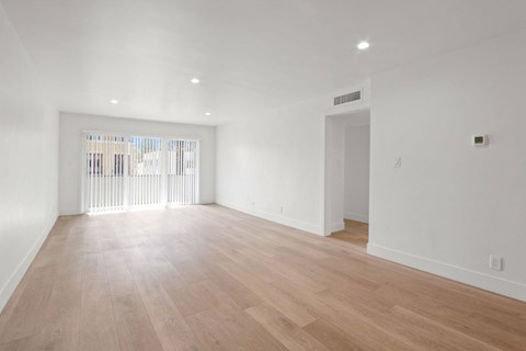 the living room and dining room of a house with white walls and wood floors