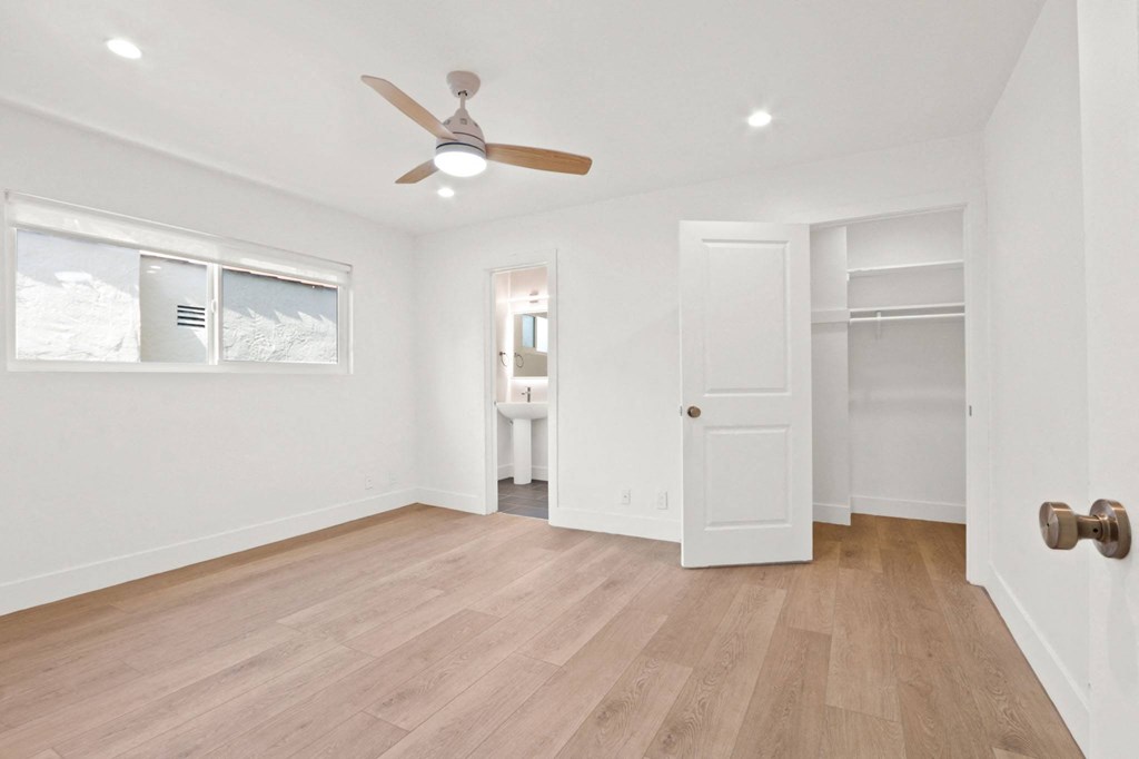 an empty living room with a ceiling fan and a closet