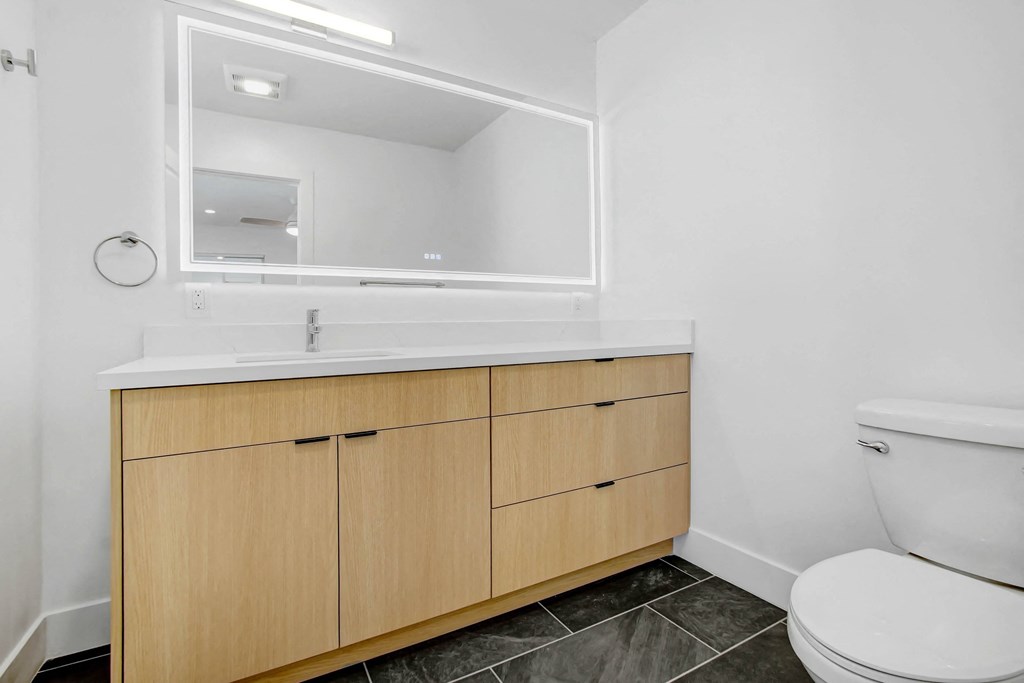 a bathroom with wooden cabinets and a toilet and a sink