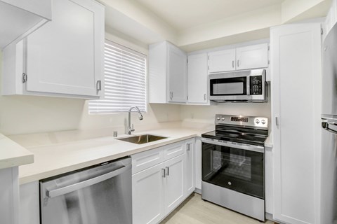 A white kitchen with a stainless steel dishwasher and oven.
