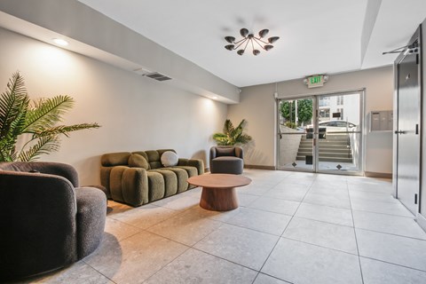 A living room with a couch, chair, and potted plant.