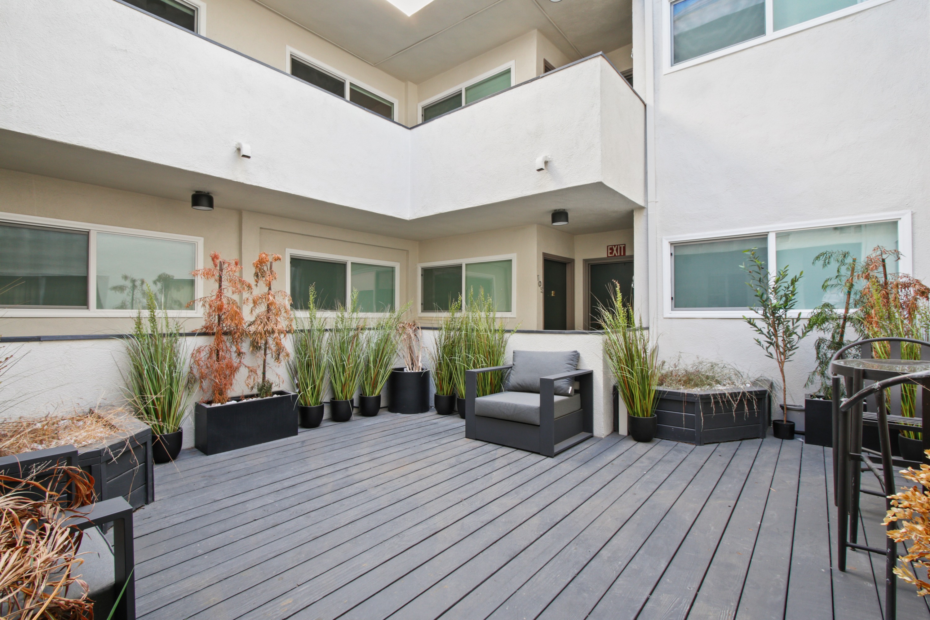 A balcony with a grey bench and black planters.