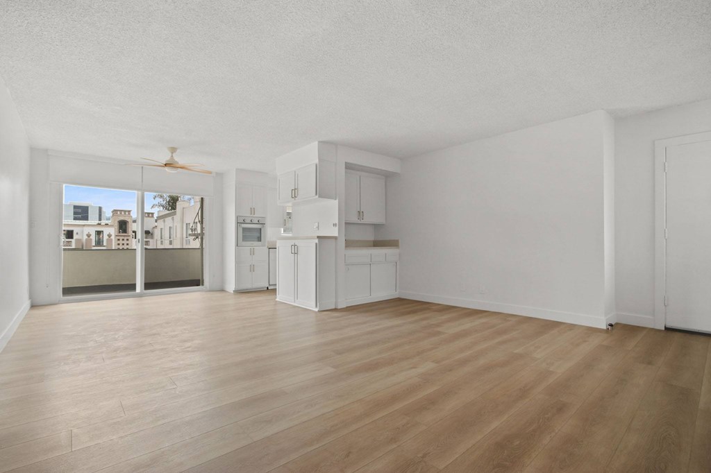 A spacious kitchen and living room with wooden floors and white walls.