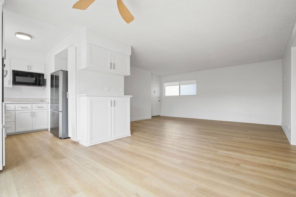 A spacious kitchen with white cabinets and a wooden floor.