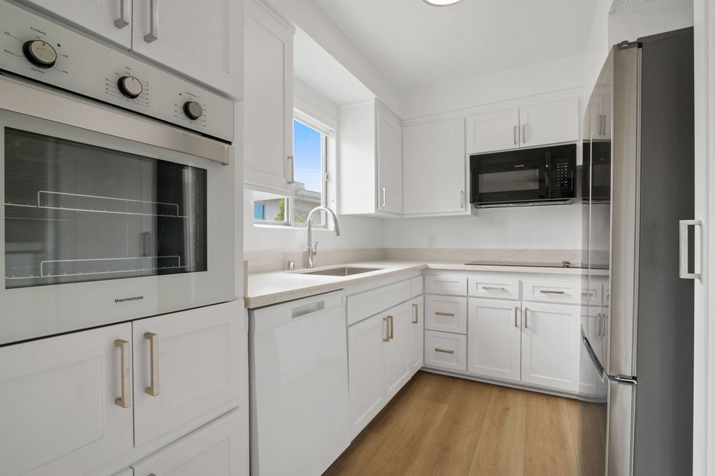 A modern kitchen with white cabinets and appliances.
