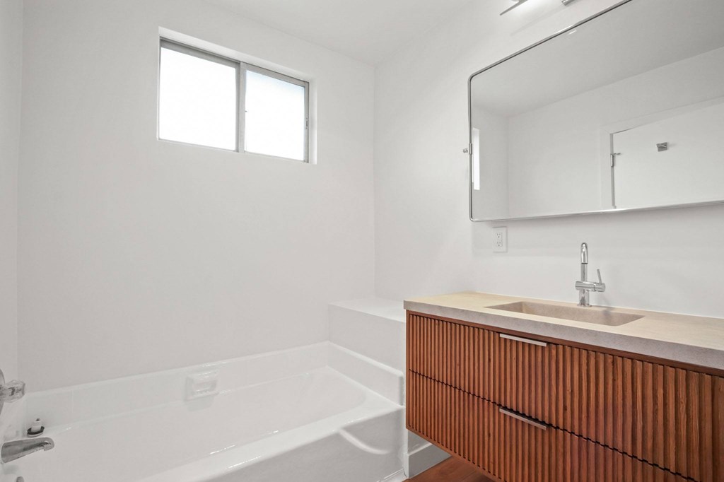A white bathroom with a wooden vanity and a bathtub.