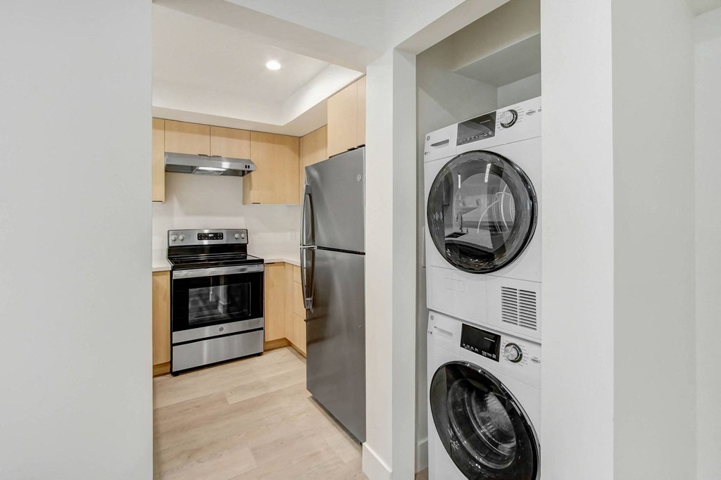 a washer and dryer in a kitchen with a stainless steel refrigerator and stove