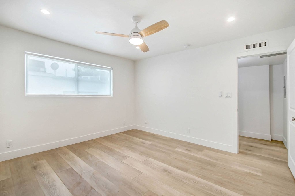 an empty living room with wood floors and a ceiling fan