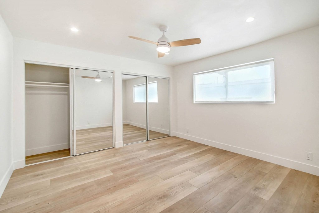 an empty room with a ceiling fan and sliding glass doors
