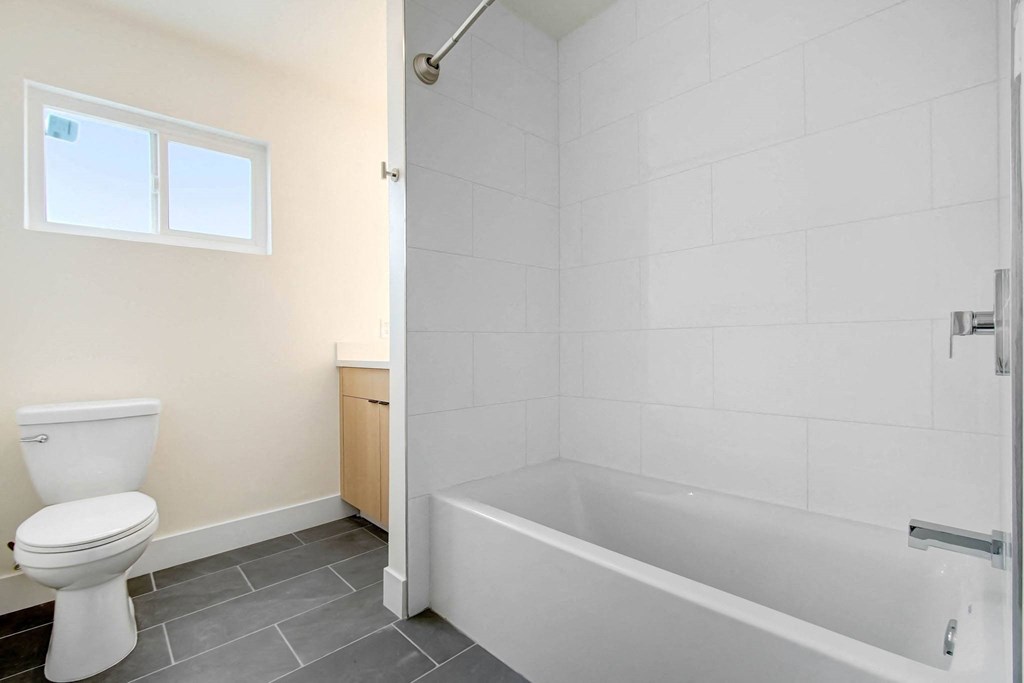 a white bathroom with a toilet and a bath tub