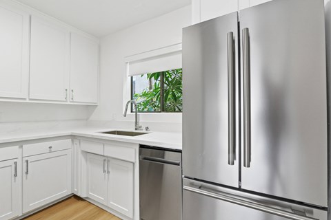 A modern kitchen with a stainless steel refrigerator and white cabinets.