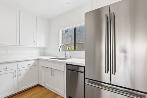 A modern kitchen with a stainless steel refrigerator and white cabinets.