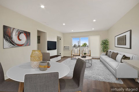 A modern living room with a white table and grey chairs.