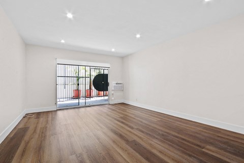 a living room with white walls and a door to a balcony