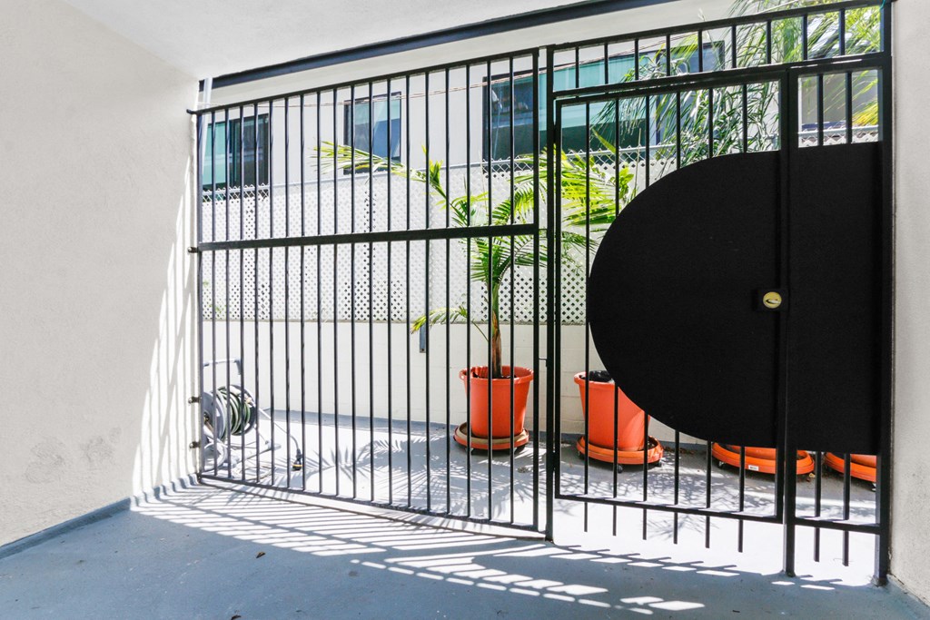 a small cage with a door and a plant in it