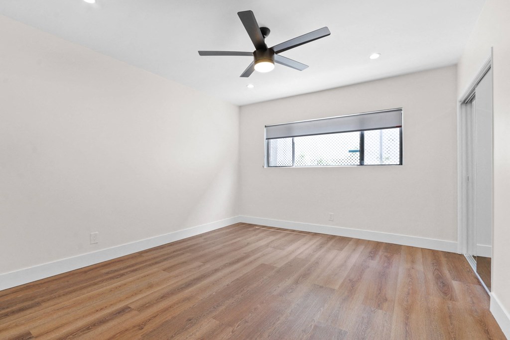 an empty living room with a ceiling fan and a window