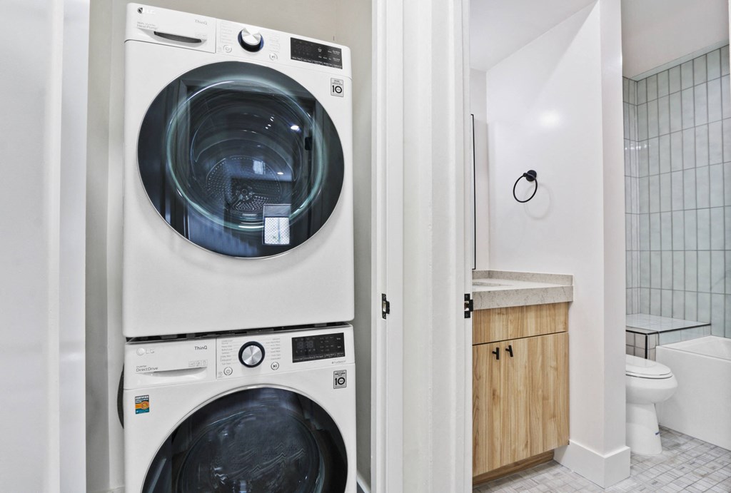 a white washer and dryer in a bathroom with a toilet and a sink