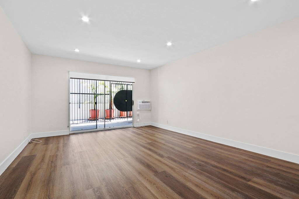 A room with wooden floors and a window with bars.