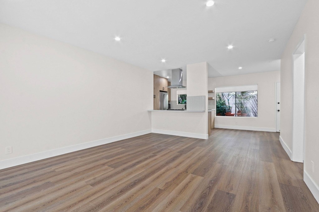 A spacious room with wooden flooring and white walls.