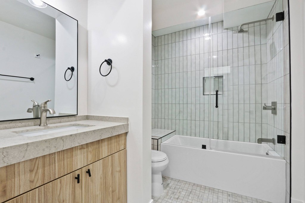 A white bathroom with a sink, mirror, and tub.
