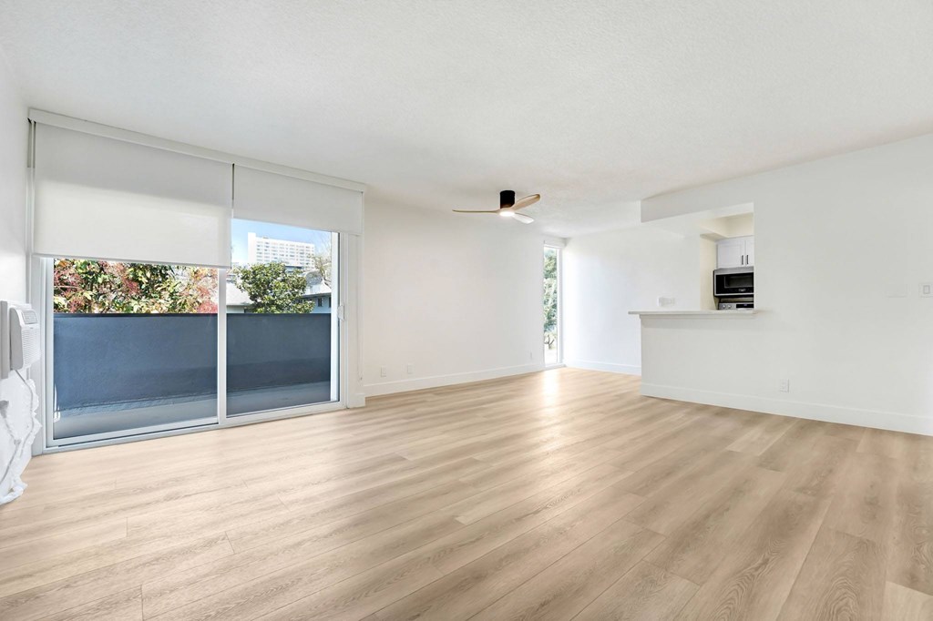 A room with wooden flooring and a window with blinds.