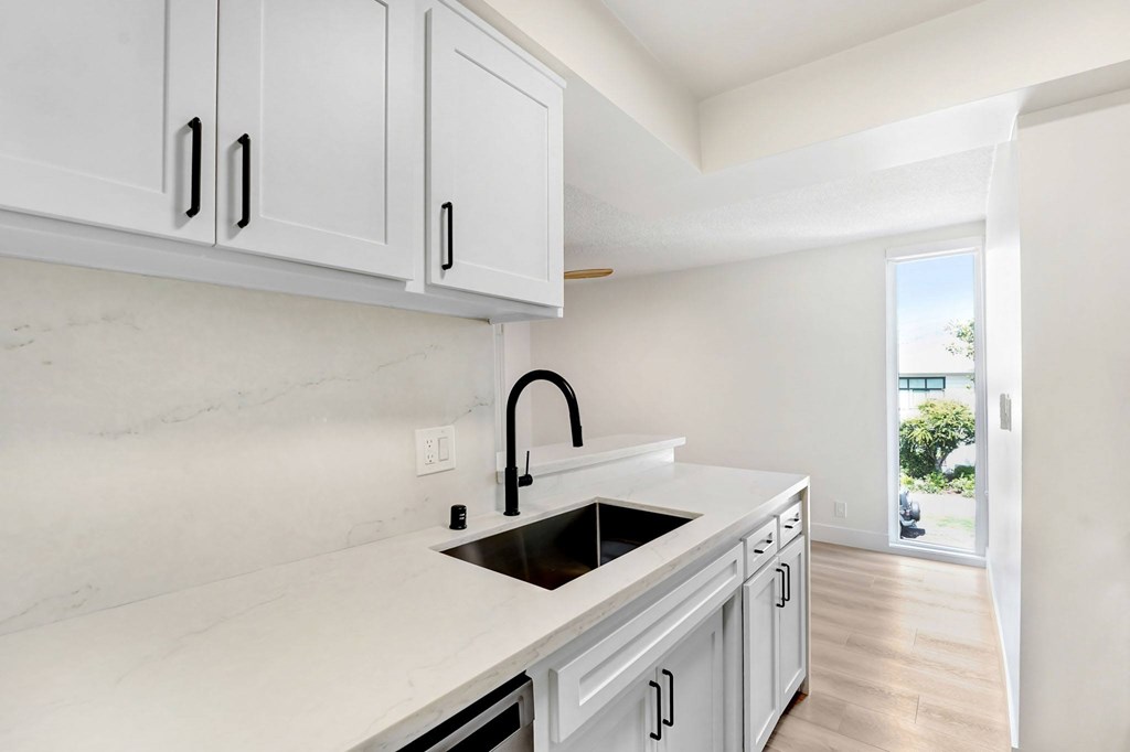 A kitchen with white cabinets and a marble countertop.