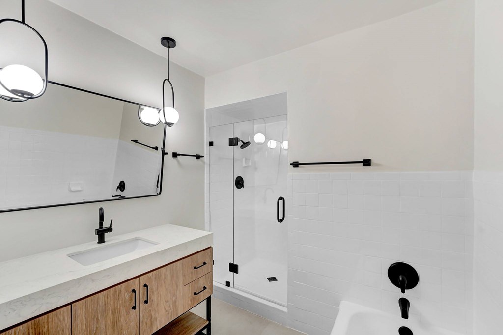 A modern bathroom with a white sink and a walk-in shower.