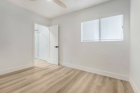 A room with a white door and a window with white blinds.