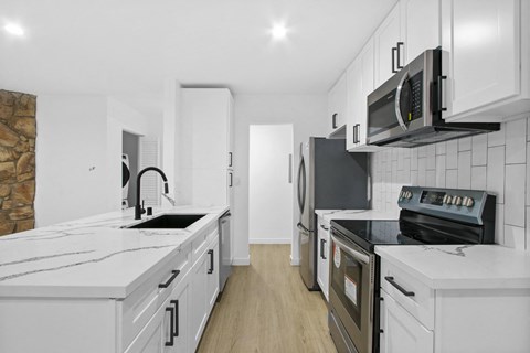a kitchen with white cabinets and black appliances and white counter tops