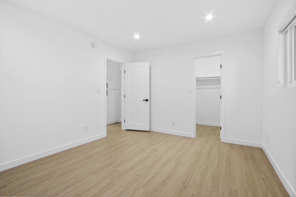 a living room with white walls and wooden floors and white doors