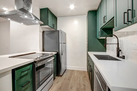 a kitchen with green cabinets and white counters and a stainless steel refrigerator