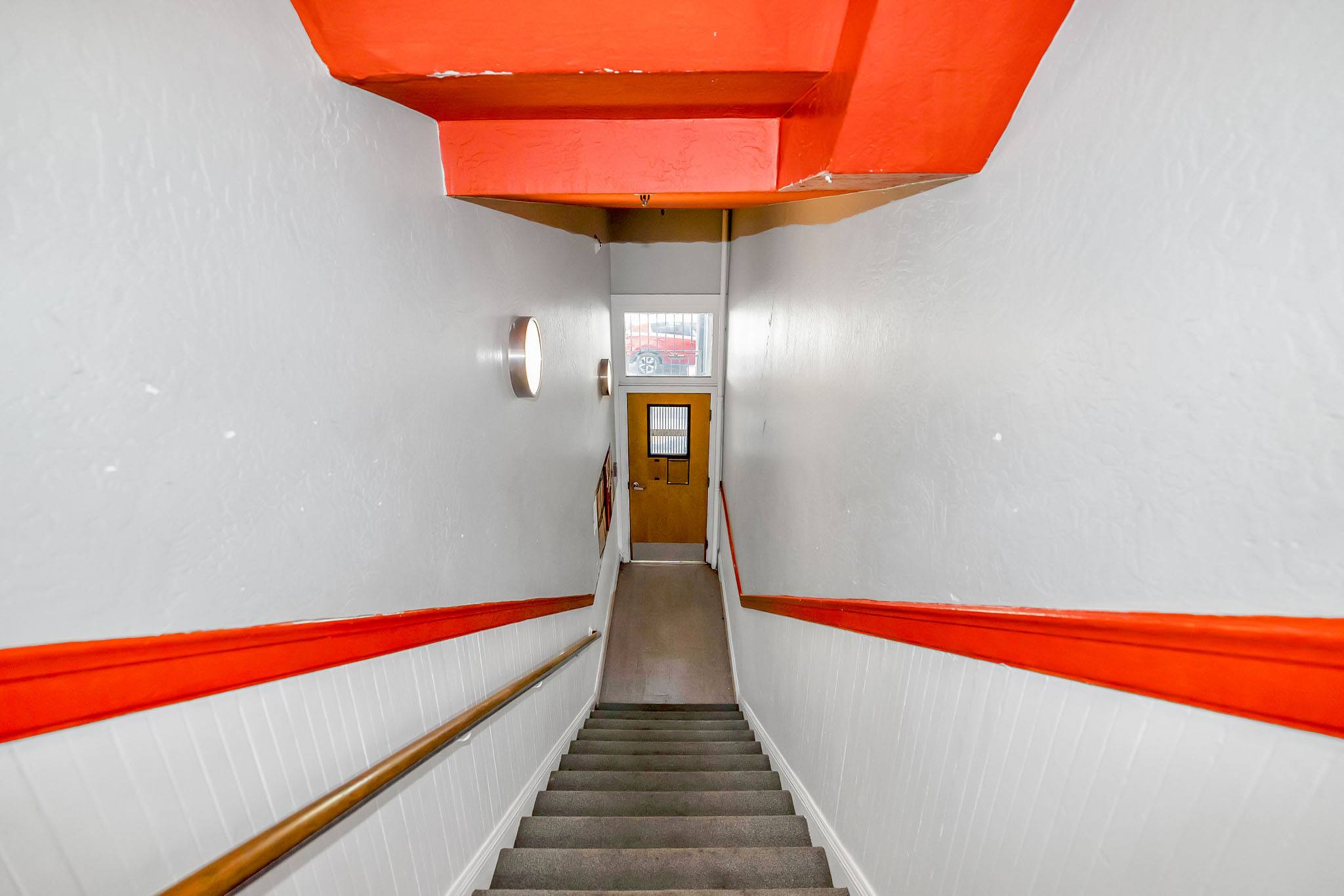 A stairway with a red handrail and white walls.