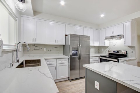 A modern kitchen with white cabinets and a marble countertop.
