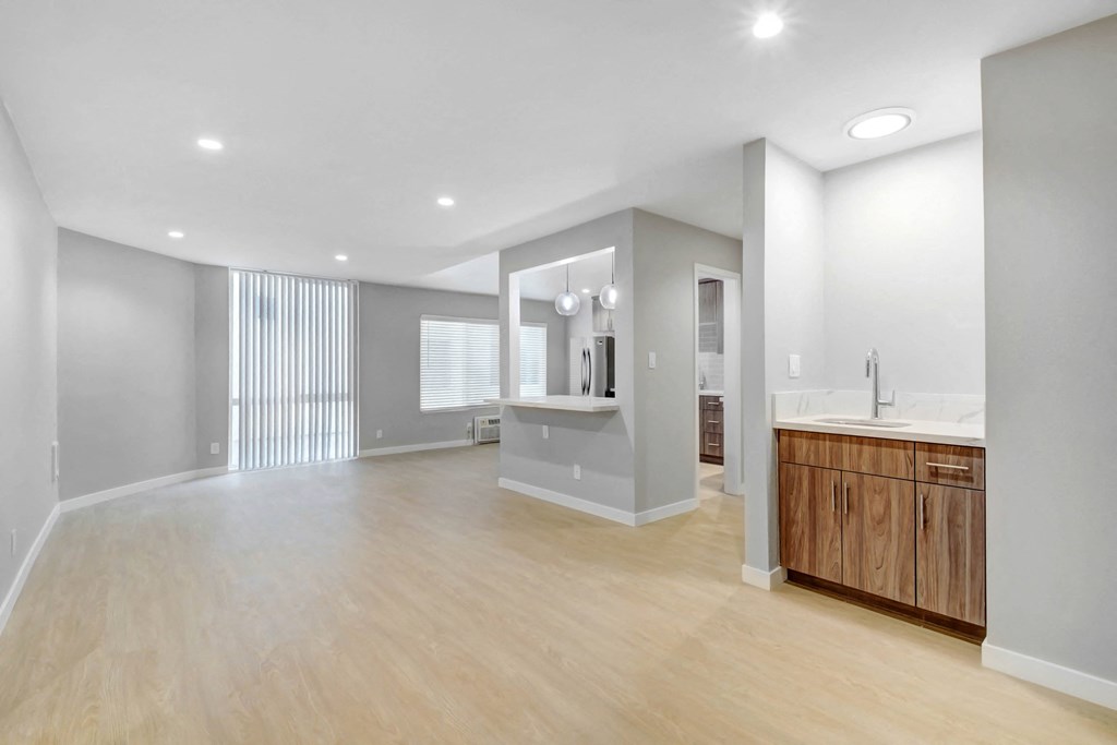 an empty living room and bathroom with a sink and a mirror