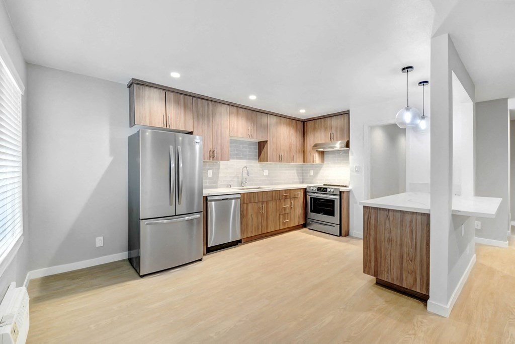 a large kitchen with stainless steel appliances and wooden cabinets