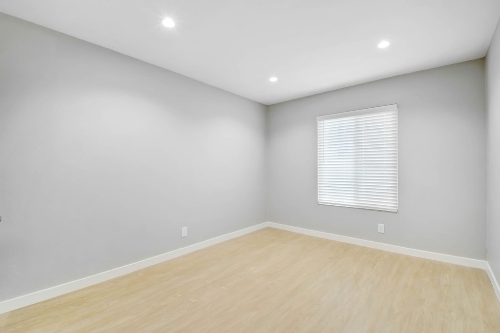 a room with white walls and wood floors and a window