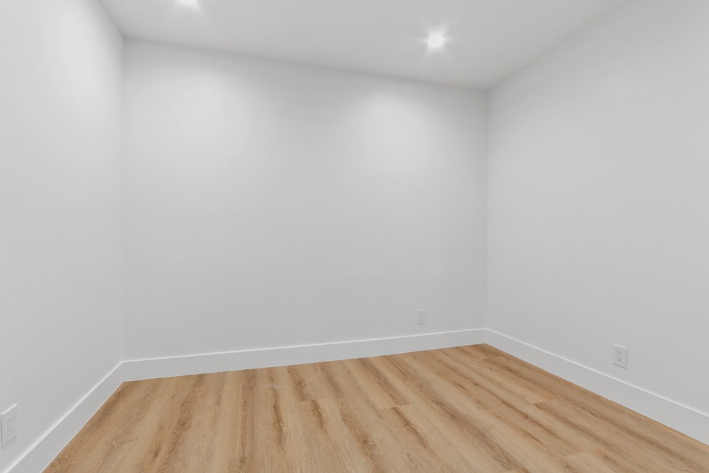 A room with wooden flooring and white walls.
