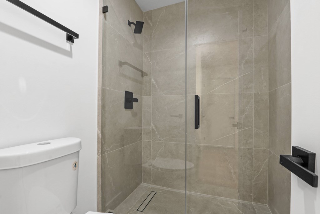 A white bathtub is in a bathroom with a glass shower door.