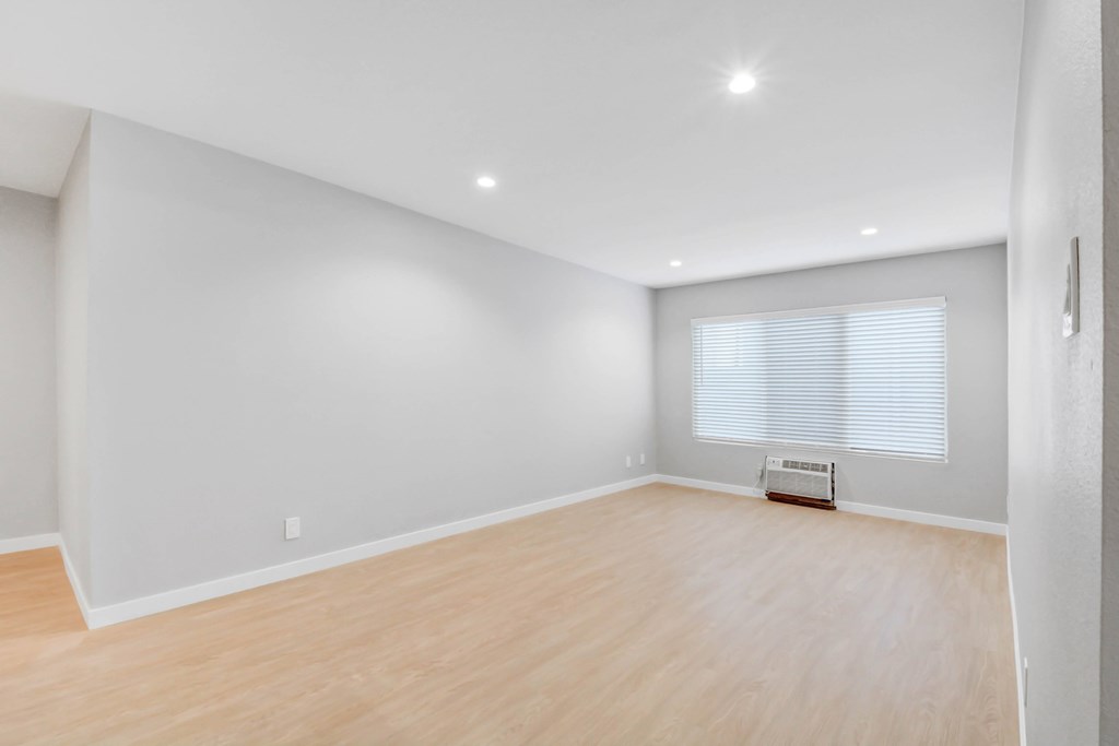 A room with wooden flooring and a window with blinds.