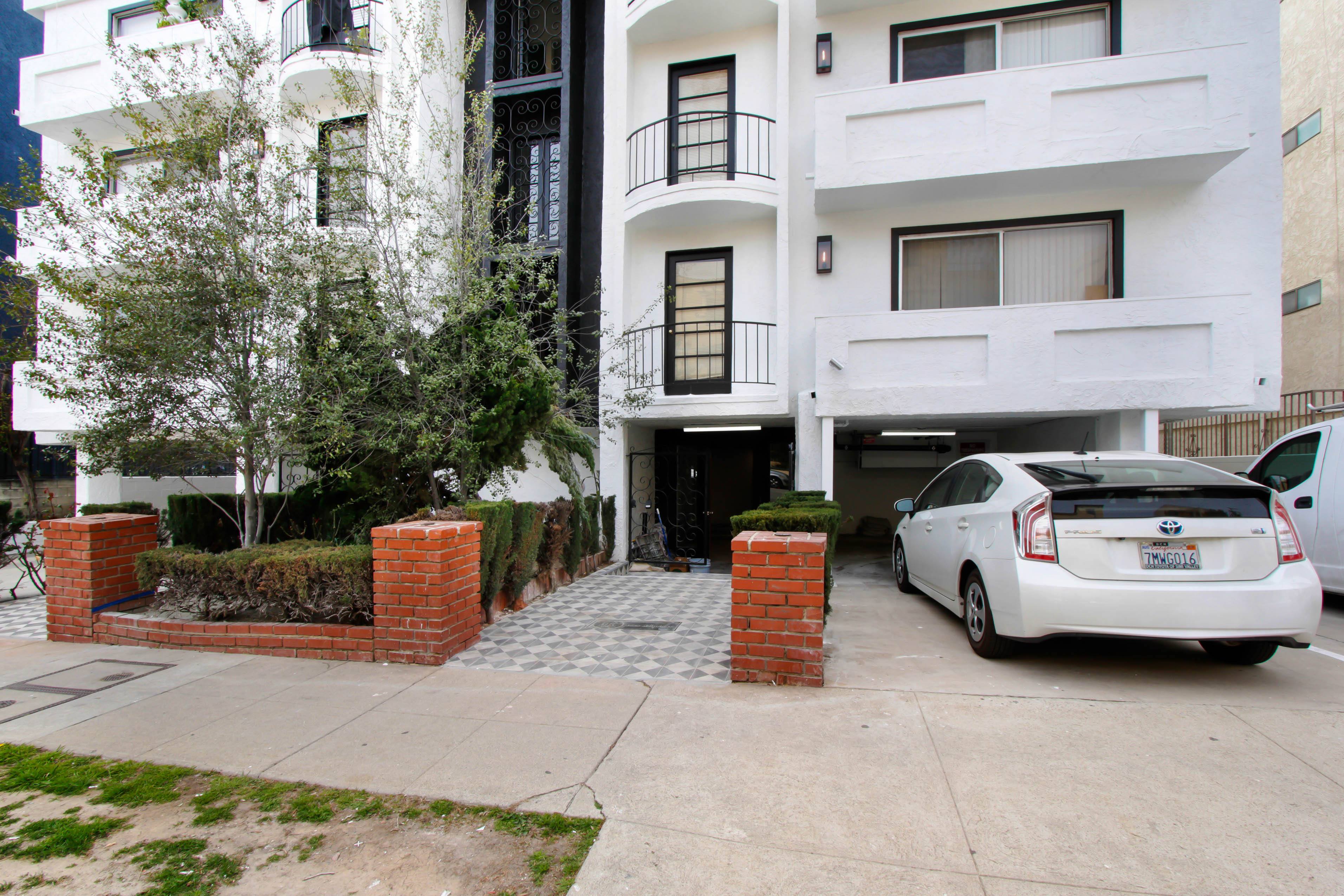 A white car is parked in front of a white building.