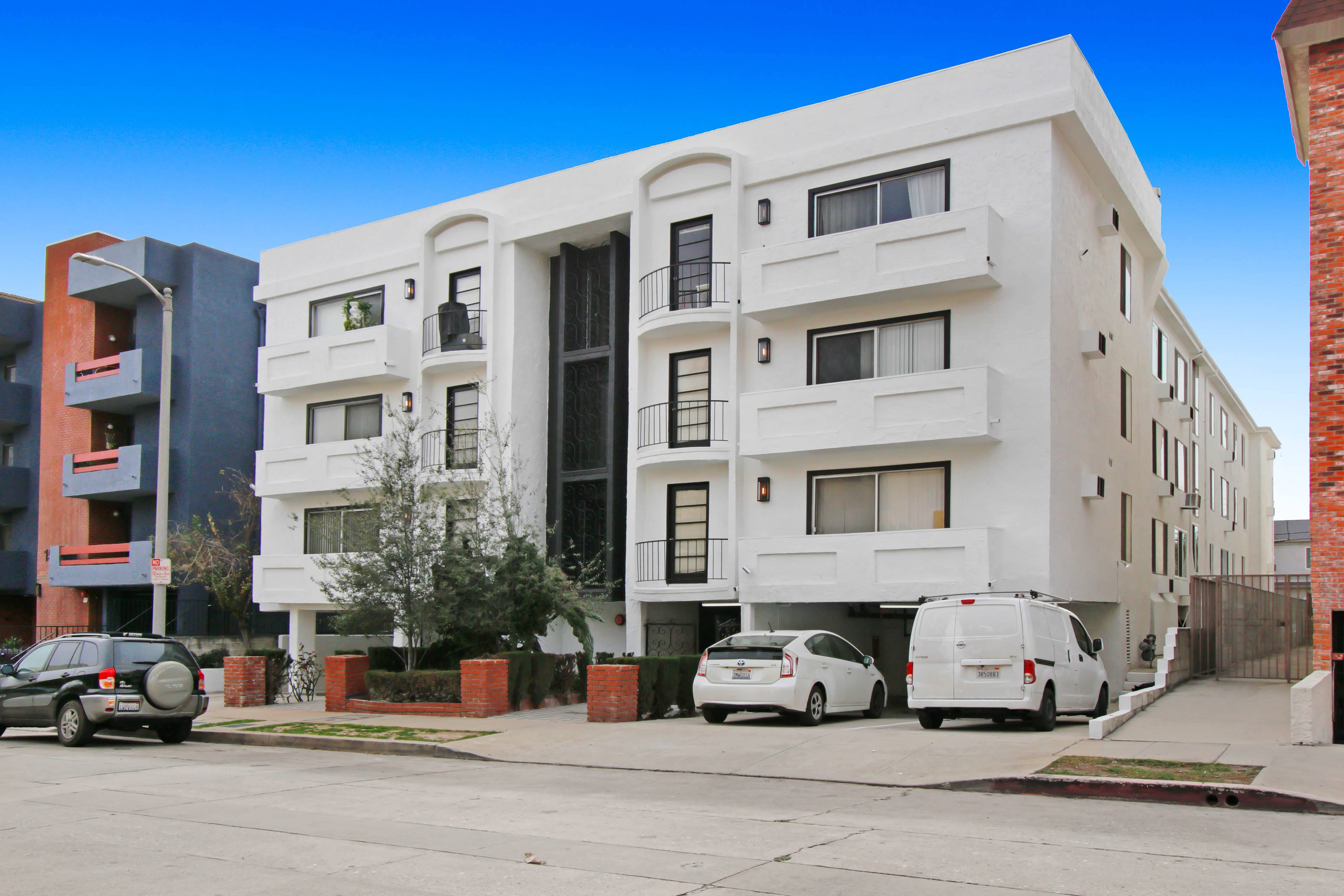 A white apartment building with cars parked in front.