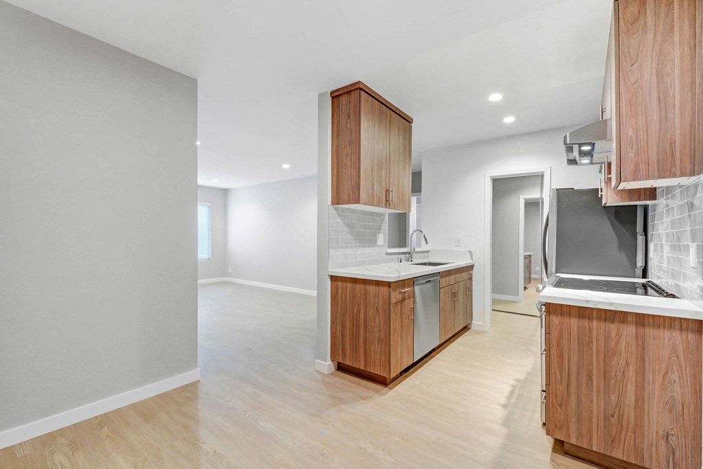 a renovated kitchen with wood cabinets and white appliances and a living room