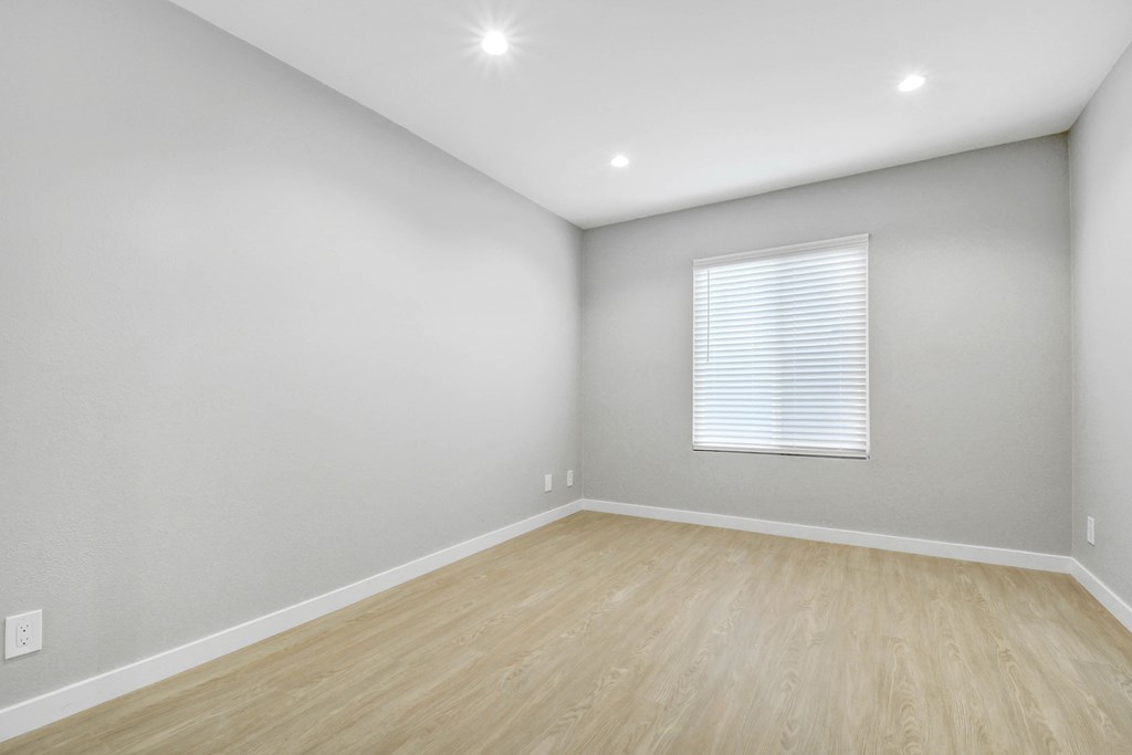 an empty room with wood floors and a window