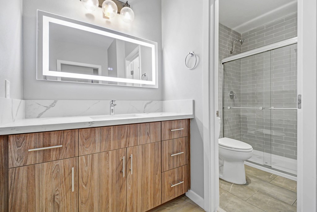 A bathroom with a white counter top and wooden cabinets.