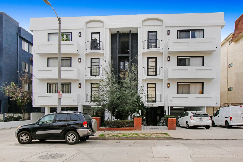 a white apartment building with cars parked in front of it